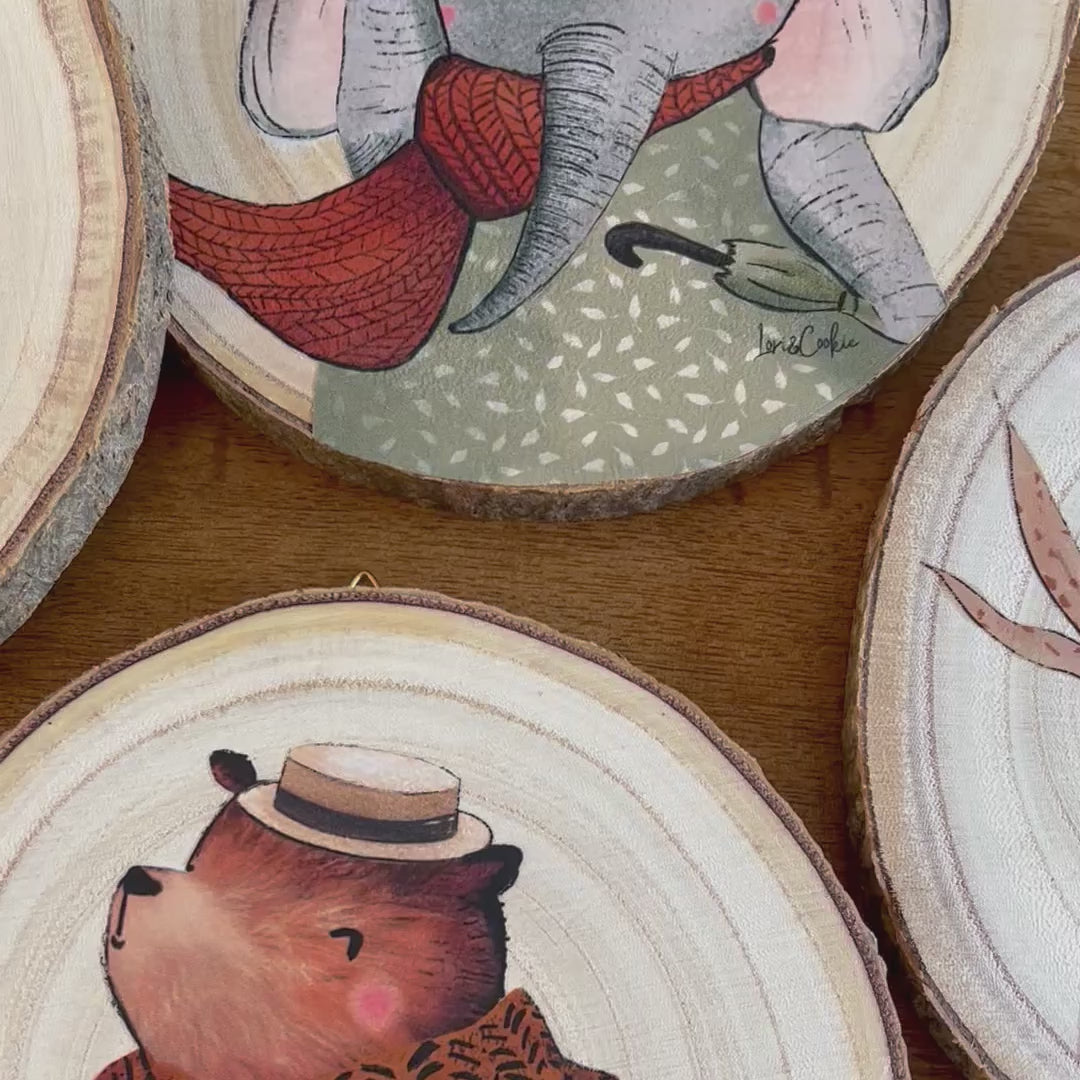 Vier dierenillustraties op houten boomstammetjes, als sfeervolle wanddecoratie in een babykamer. Natuurlijke uitstraling met warme kleuren.